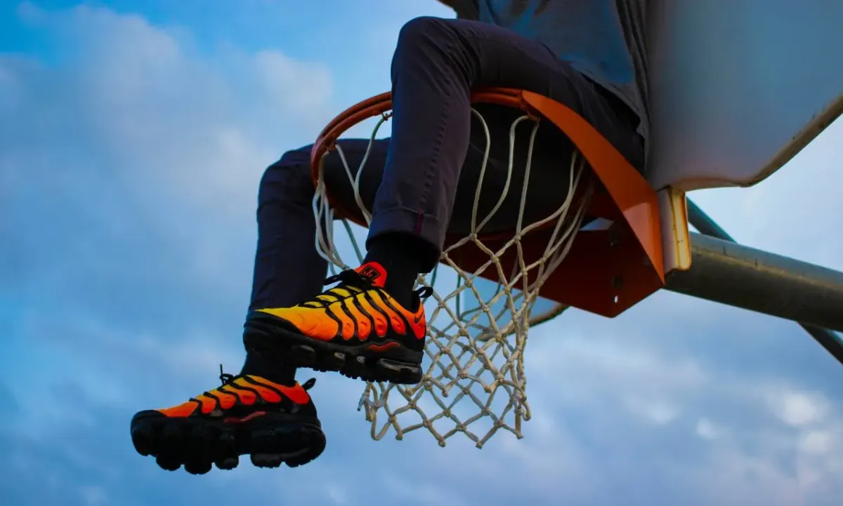 Person sitting on a basketball hoop rim wearing sneakers, in an outdoor setting unrelated to tax residency or the substantial presence test
