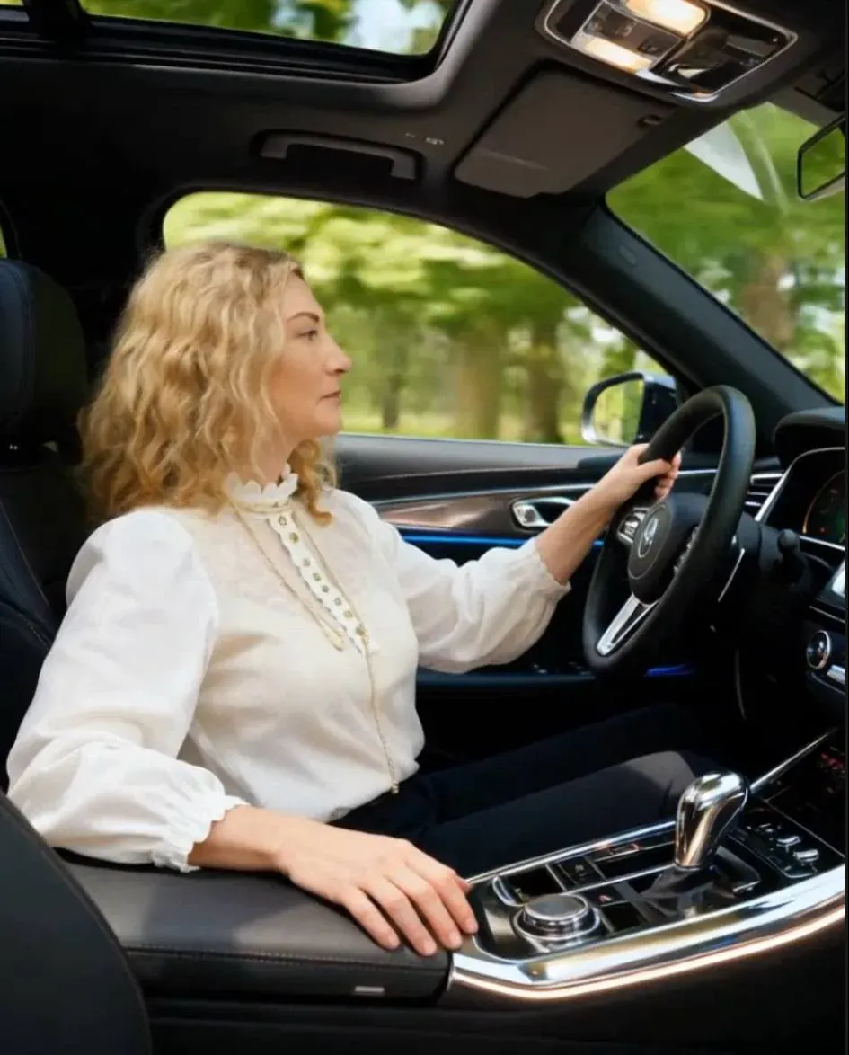 Woman driving a car with hands on the steering wheel, seen from inside the vehicle