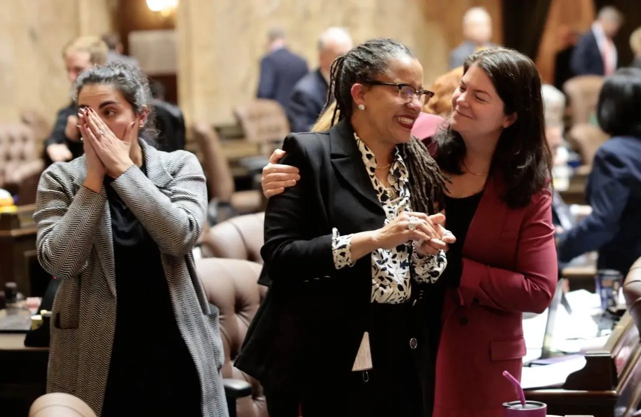 Three women smiling and talking together in an office-like social setting